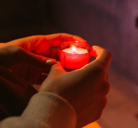 person holding red candle in a dark room pexels-photo-3943933