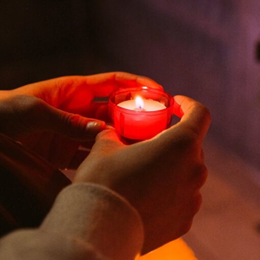 person holding red candle in a dark room
