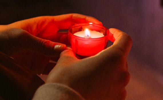 person holding red candle in a dark room