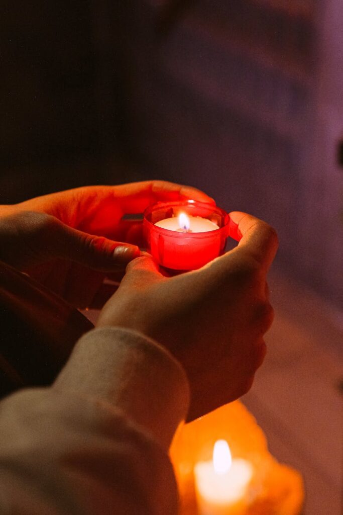 person holding red candle in a dark room pexels-photo-3943933