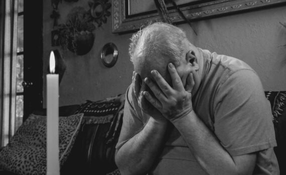 grayscale photo of man covering his face with hands