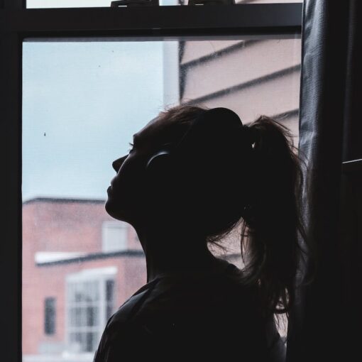 silhouette photo of a woman looking through window