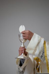priest holding a chalice and communion bread