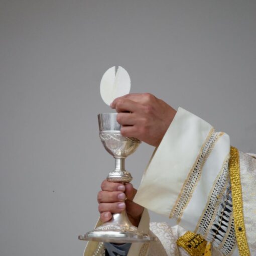 priest holding a chalice and communion bread