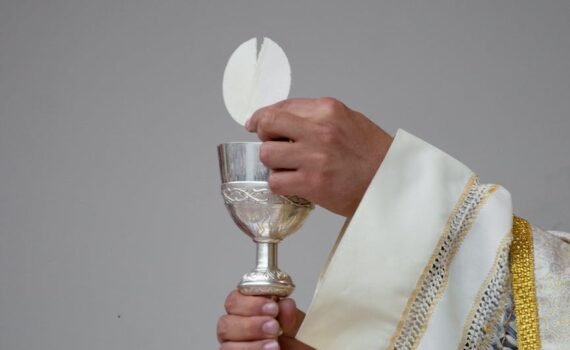 priest holding a chalice and communion bread