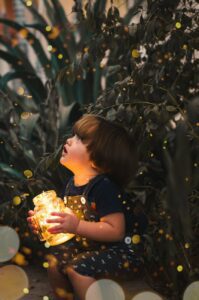 child holding clear glass jar with yellow light