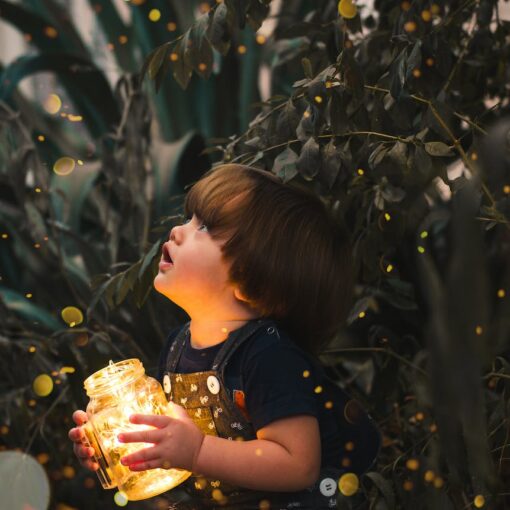 child holding clear glass jar with yellow light