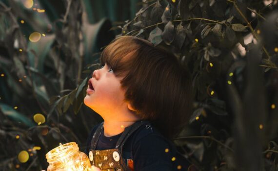child holding clear glass jar with yellow light