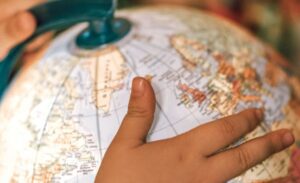 small kid spinning globe with physical map of world