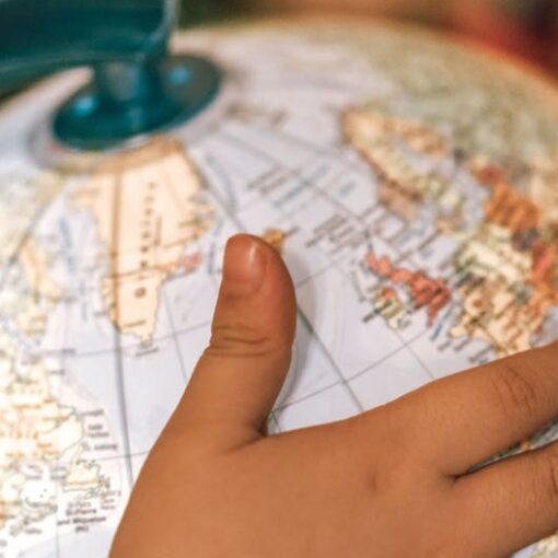 small kid spinning globe with physical map of world