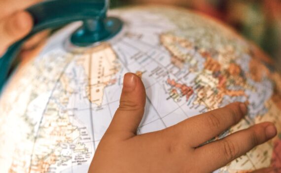 small kid spinning globe with physical map of world