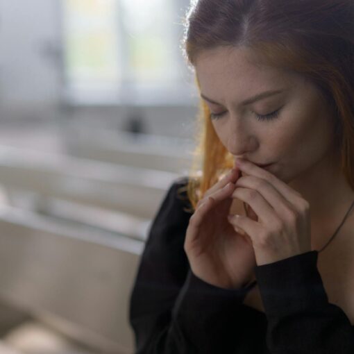 a woman in black long sleeves praying with her eyes closed